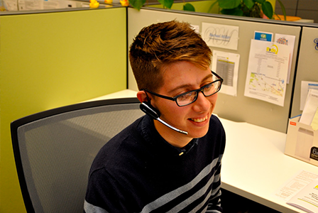 A Ride Connection employee wearing glasses is answering a phone call by using a headset