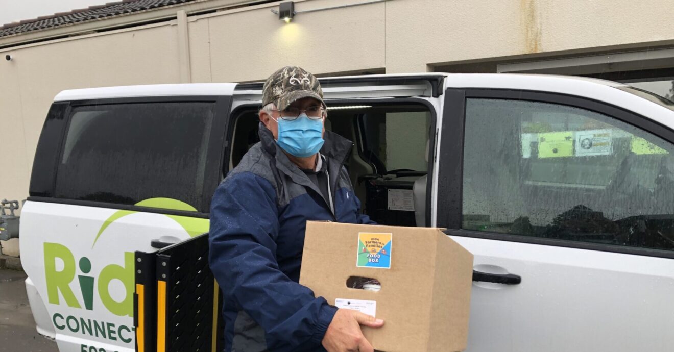 An older male Ride Connection driver with Centro food box at van